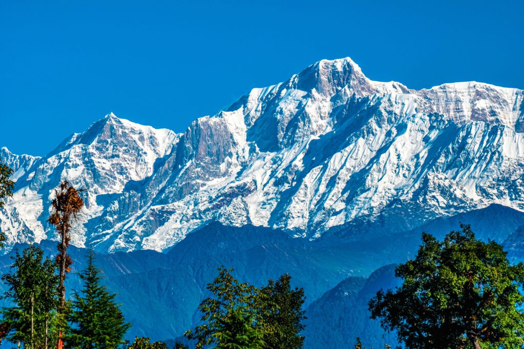 Breathtaking view of snow-covered peaks in the Himalayas from Chopta, India, showcasing natural beauty.