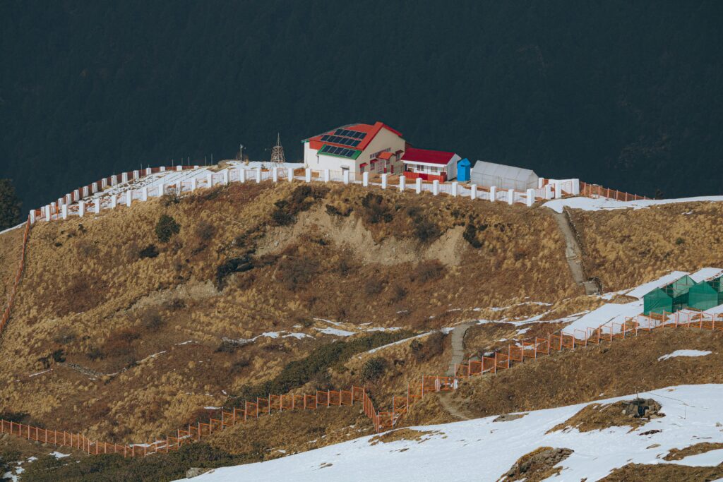 A remote building with solar panels on a snowy hilltop in Auli, India.